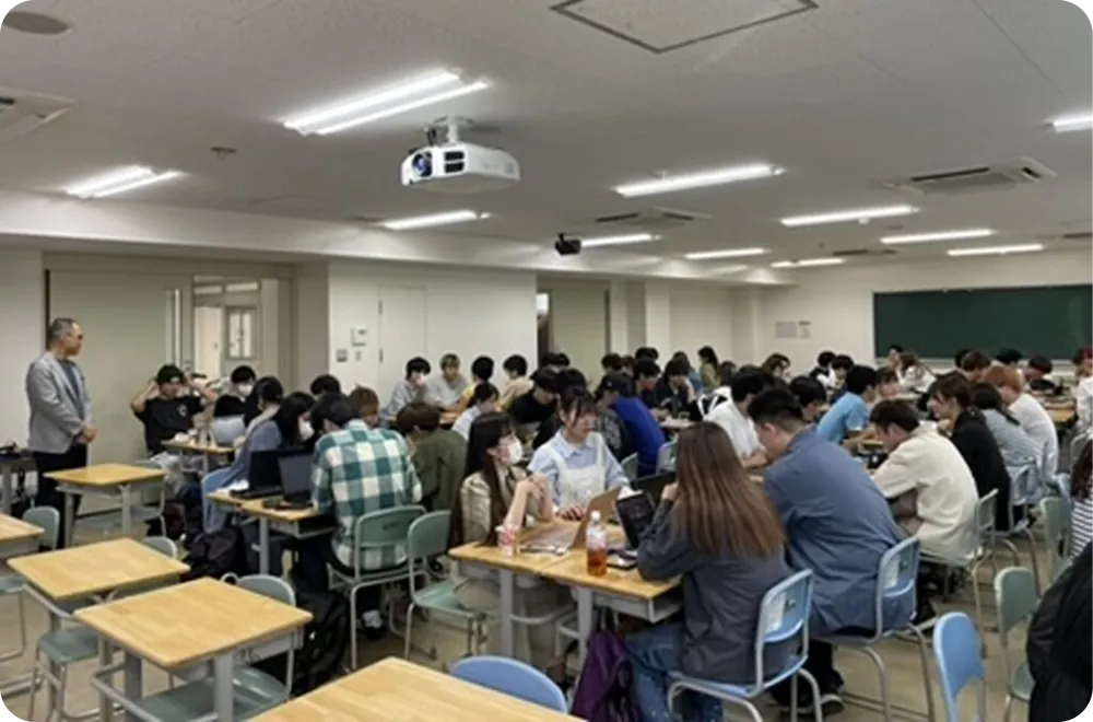 大学の教室で、学生たちがグループに分かれてディスカッションや作業を行っている様子