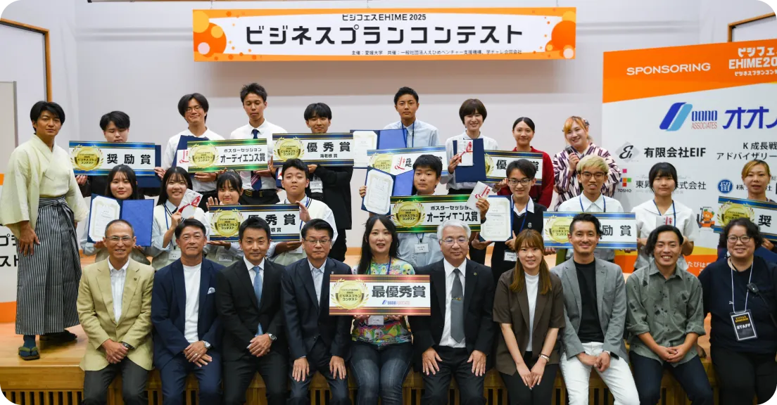 ビジネスプランコンテストEHIME2025の表彰式で、受賞者と関係者が賞状や盾を持って並ぶ集合写真